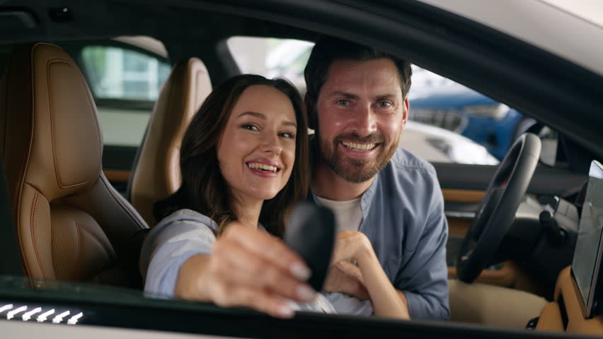 Caucasian couple man woman girl guy female male family hugging cuddling happy smiling looking at camera celebrate buying own vehicle transport holding key in new car buying auto inside automobile