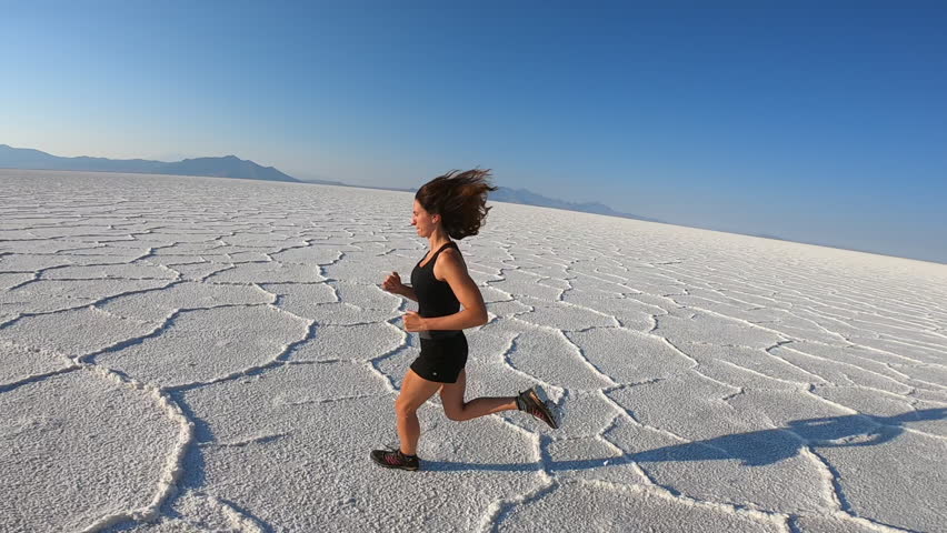 Jogging across the Bonneville Salt Flats, an expansive salt plain with stunning white patterns under a vast sky in Utah.