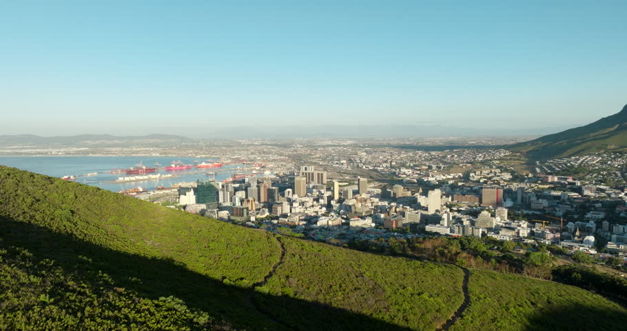 Establishing aerial view of Cape Town with Downtown, Ocean bay, Port and Mountains. Cityscape with warm golden light at summer sunset. Stunning shot with wide panorama from drone in 4K