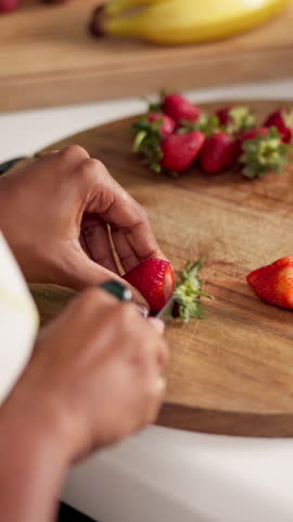 Hands, person and cutting of fruit in kitchen with healthy snack, nutrition diet and morning breakfast. Closeup, woman and chopping strawberry with organic ingredients, vegan salad and detox at house