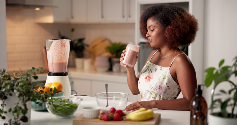 Glass, woman and drink smoothie for health, wellness and vegan diet for breakfast in kitchen. African person, fruit juice or organic protein shake for detox, weight loss or nutrition benefits in home