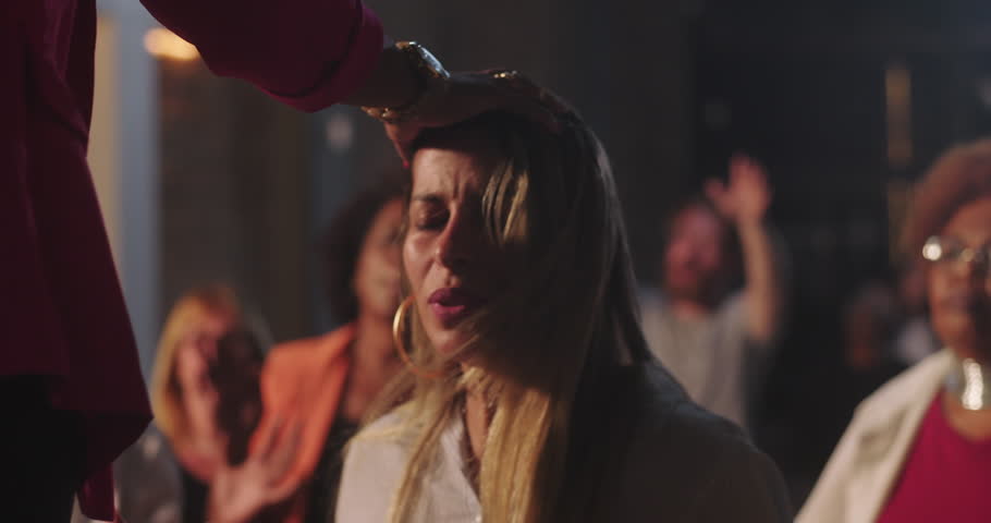 Preacher blessing woman with hands raised in worship, deep emotional prayer moment surrounded by diverse congregation, sacred atmosphere in spiritual gathering