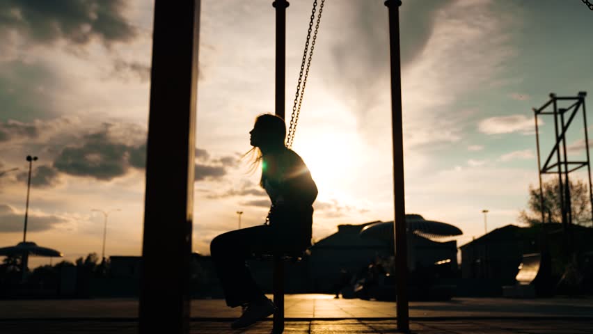 Happy female children silhouette swinging swing at summer sunset sunrise sky outdoor sport playground. Girl kids adolescent having fun flying enjoy leisure activity childhood recreation joyful playing