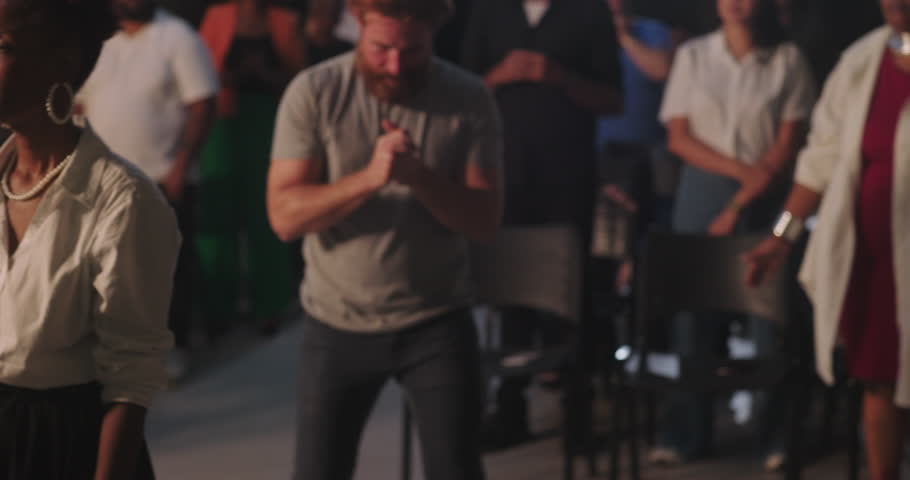 Man with hands on chest in deep prayer during spiritual gathering, surrounded by diverse congregation, African American woman praying beside him, faith and devotion emphasized