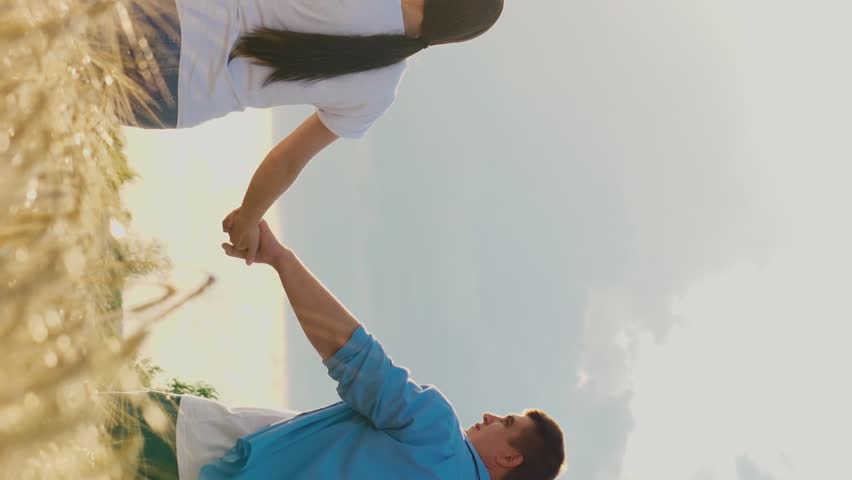Happy family holding hands walking at bright sunny dry wheat field back view. Mother father son and daughter with love going cereal harvest plantation natural sunlight sky horizon agriculture scenery