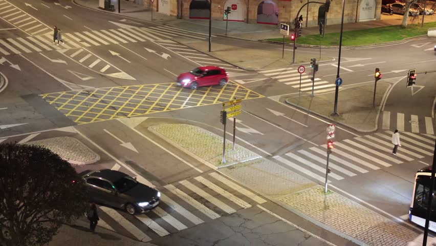 A serene view of empty urban streets at night showcasing crosswalks, traffic signals, and a lone pedestrian highlighting the stillness of the city.
