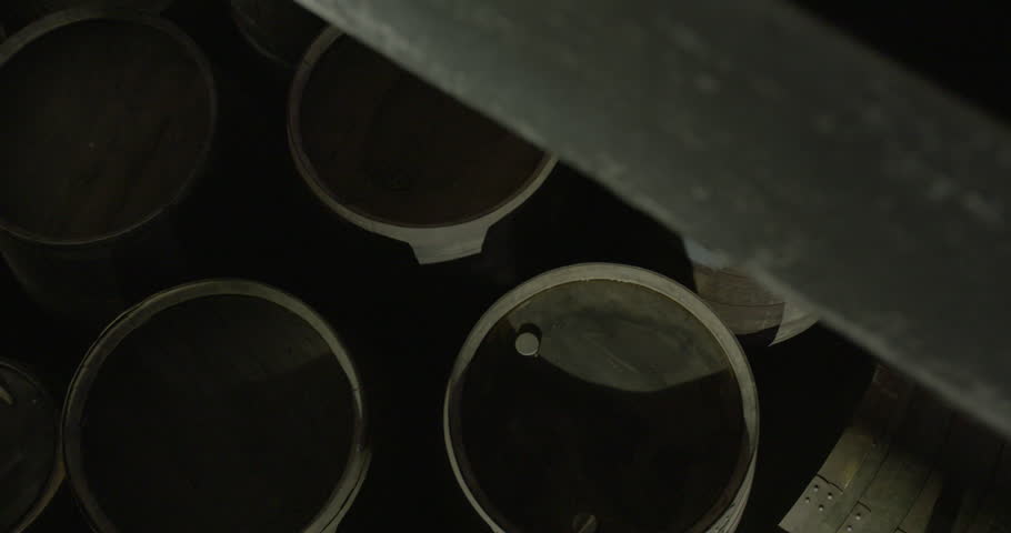 Whiskey wine barrels wooden kegs overhead warehouse jib shot