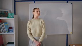 Closeup serious schoolteacher posing camera against board in classroom. Portrait educator woman standing with calm face expression. Confident young teacher looking straight in school class interior  - Powered by Shutterstock - Get 15% off with code: PIKWIZARD15