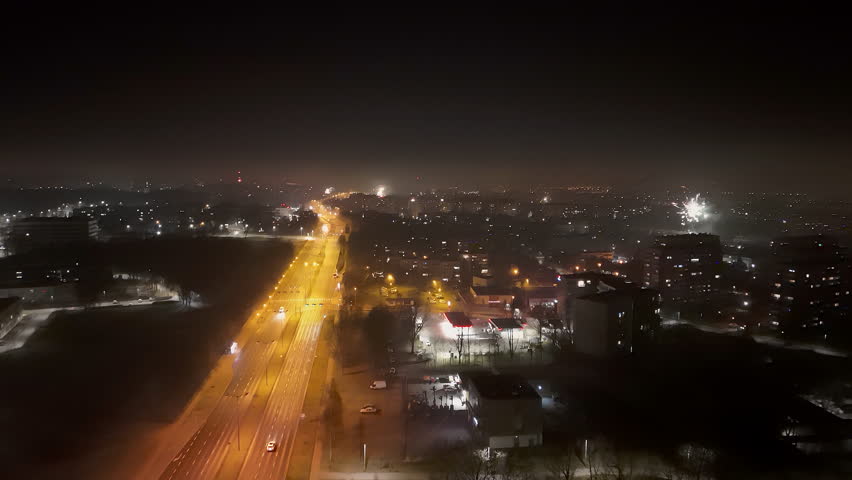 Night aerial view of city with fireworks and illuminated streets, Multiple fireworks lighting up the night sky above a city