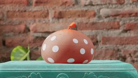 Red Polka Dotted Balloon Exploding With Red Liquid Upon Impact With A Stone. - Powered by Shutterstock - Get 15% off with code: PIKWIZARD15
