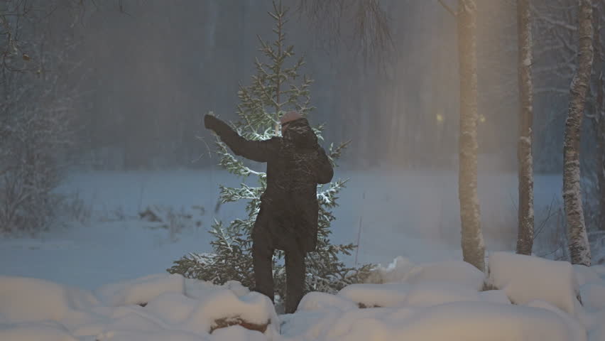 Woman decorating outdoor christmas tree in harsh winter storm.