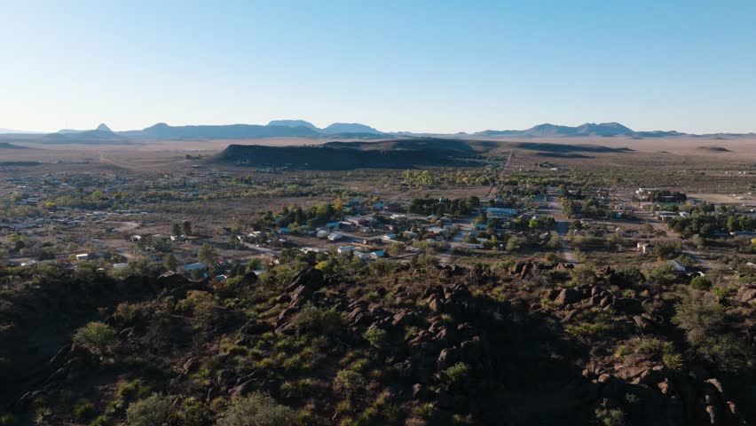 Aerial orbit overlooking rural Texas town at sunrise from mountaintop, West Texas
