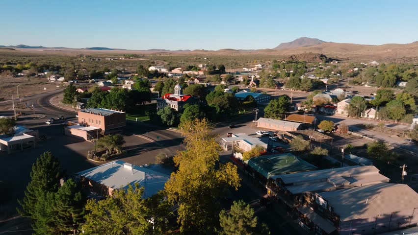 Orbiting city hadll in small rural Texas town at sunrise, single car drives on empty road, aerial 4k