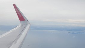 view through plane window from inside airplane cabin while climbing flying over the sky with airplane wing winglet and fluffy cloud outside in summer daytime - Powered by Shutterstock - Get 15% off with code: PIKWIZARD15