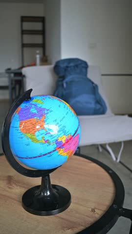 Vertical video of two women friends taking backpack for leaving apartment, globe on table.