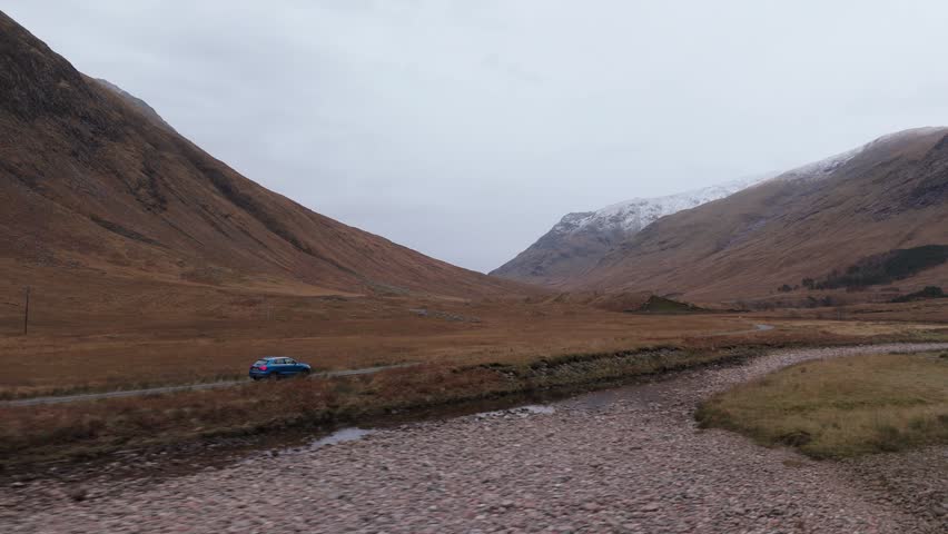 Cinematic tracking shot of a car driving through Glen Etive moors in Scotland