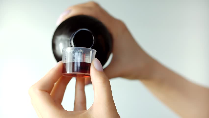 Medicine Antipyretic Syrup. Flu Sick Antibiotic. Pharmacy Healthcare Sick Treatment. Pours Cough Syrup Into Spoon.Liquid Medicine Cure Pharmaceutical Flu.Pouring Liquid Medicine Onto Spoon For Healing