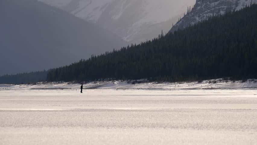 Hockey skater on a frozen lake in Kananaskis country. Spray Lakes.