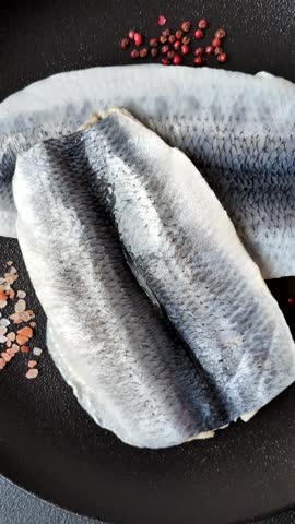 Herring fillet salted and marinated with salt, spices and oil on a dark concrete background