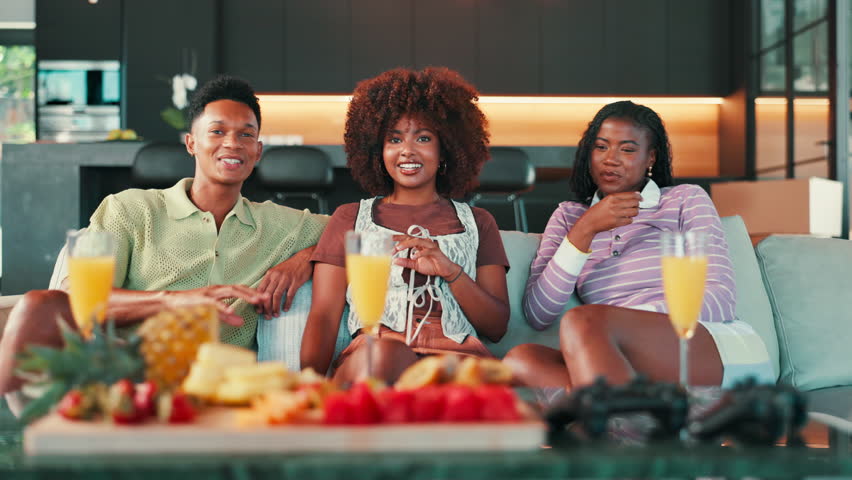 Laughing, conversation and people on sofa with snacks for gathering, reunion or chill on weekend. Mimosas, fruit and group of friends talking, relaxing and having fun together in living room in home.