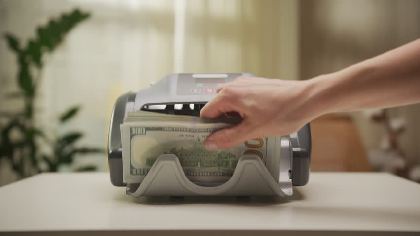 Money counting machine processing stacks of hundred-dollar bills
