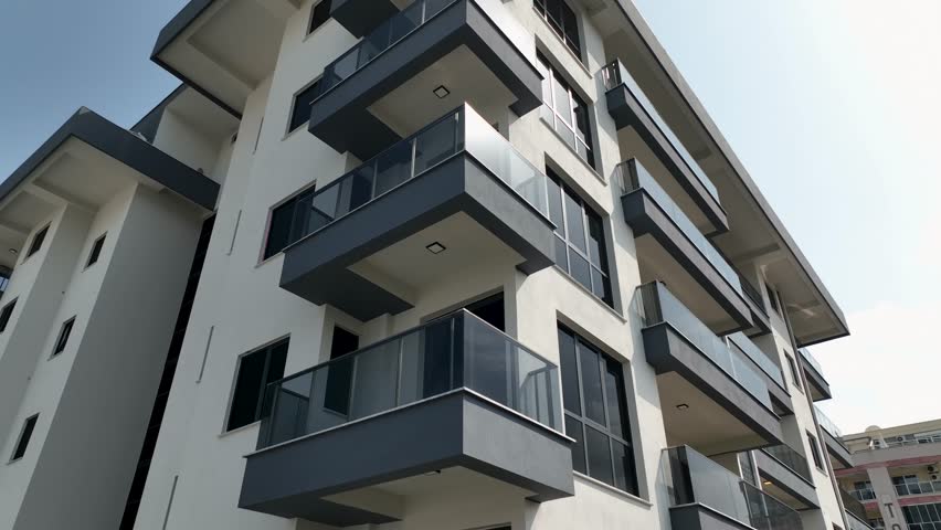Aerial View: The modern facade of a residential complex features clean lines, balconies, and dark reflective windows.A stunning urban architectural design.