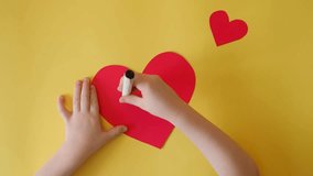 Toddler writes a self-cut heart card for mother congratulations on March 8, birthday, mother's day. Plain yellow background, red hearts Carefully and lovingly decorates the card. Gratitude to parents - Powered by Shutterstock - Get 15% off with code: PIKWIZARD15