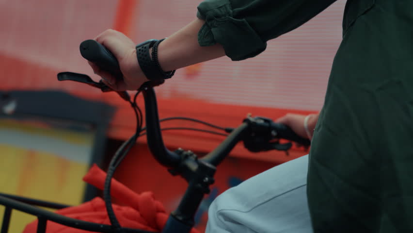 Close up on woman cycling on small compact electric bicycle in city. E-bike rider on a bike lane. Cargo bicycle with transportation basket in front. Urban transportation and modern mobility