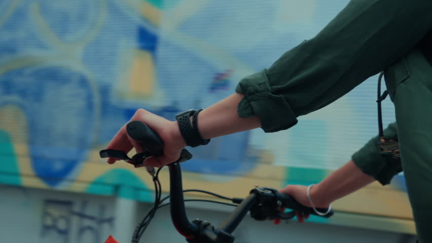 Close up on woman cycling on small compact electric bicycle in city. E-bike rider on a bike lane. Cargo bicycle with transportation basket in front. Urban transportation and modern mobility