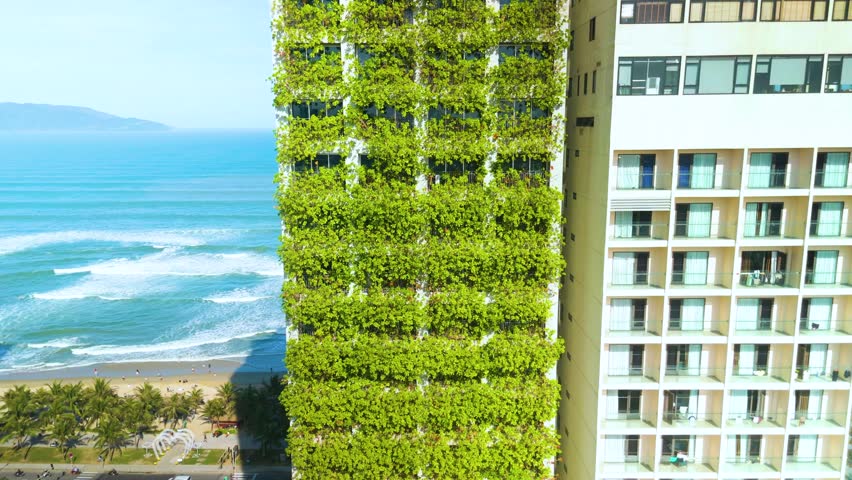 Modern green faced building rising near coastline, embodying sustainable urban design with environmentally conscious architectural elements