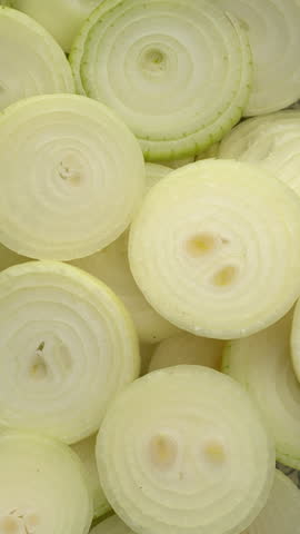 Raw sliced yellow onion background. Table spin. Vertical video.