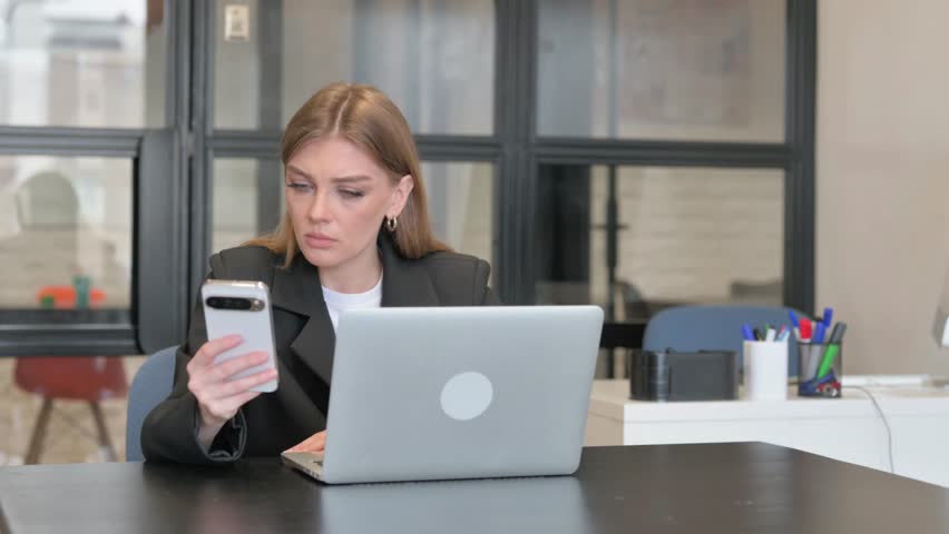 Young Businesswoman Using Phone with Laptop
