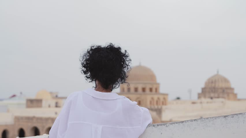 Stylish woman tourist enjoys view of Great Mosque of Kairouan in Tunisia
