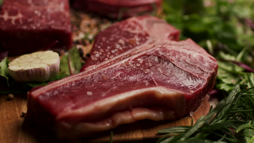 Raw Beef Steaks on Table, T-bone and Osso Buco cuts, handheld camera
