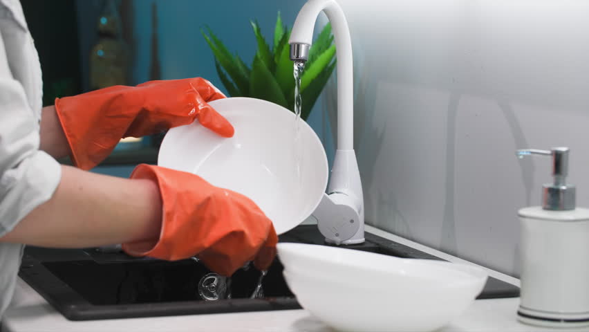 housework, young housekeeper in protective gloves rinsing foam from detergent from dishes under water in kitchen sink, close-up - Powered by Shutterstock - Get 15% off with code: PIKWIZARD15
