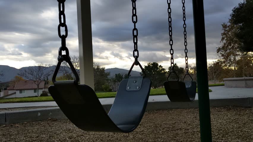 A time-lapse of a swing set in the park on a cloudy evening