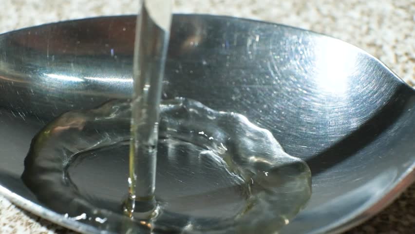 White wine vinegar is poured into spoon, macro slow motion