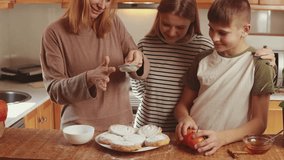 Caring mother teaching kids, dusting homemade pumpkin cookies with powdered sugar, creating sweet family memories during autumn baking time in warm kitchen - Powered by Shutterstock - Get 15% off with code: PIKWIZARD15