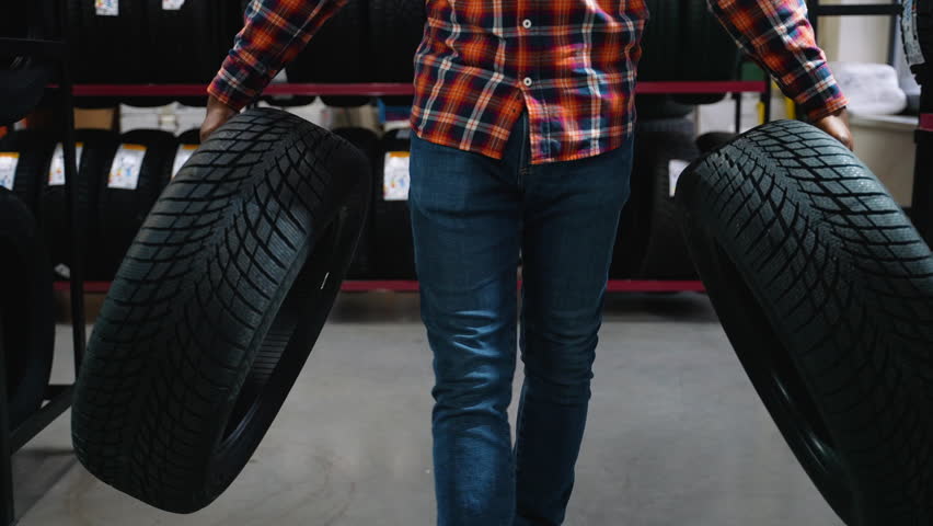 Man buying two new tires in an auto parts store