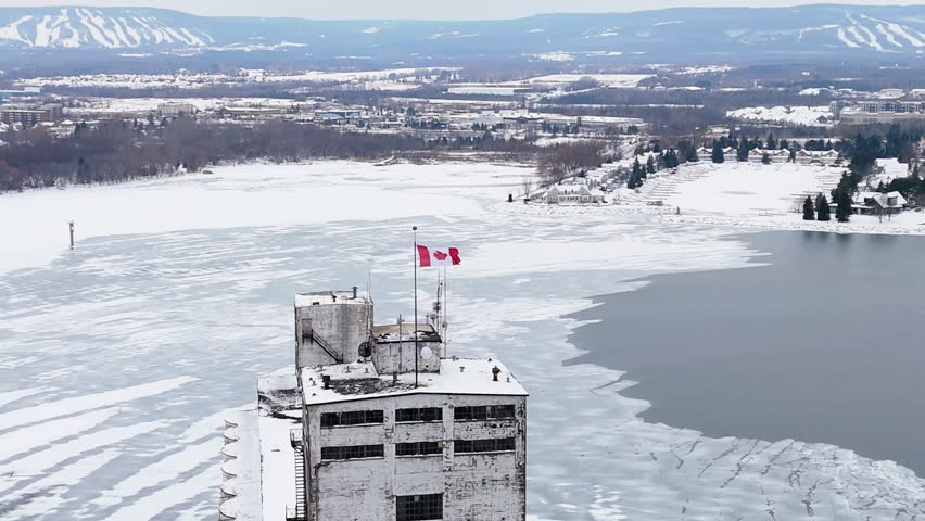 An aerial footage of the Canadian flag on a snow-covered old building in Millennium Overlook Park, Collingwood, Ontario, Canada