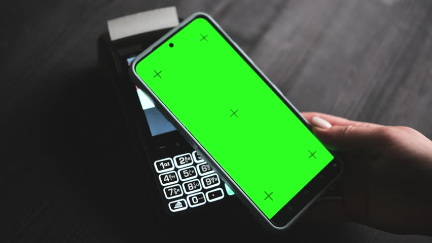 Girl Paying With Smartphone On A Terminal With A Green Chroma Key Screen And Blank For Your Design On A Screen