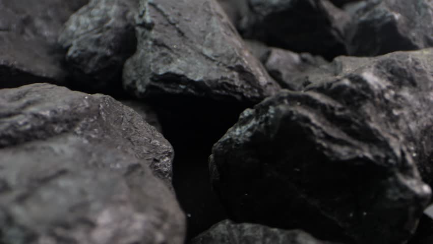 Close-up of coal fragments shifting slowly. A detailed macro shot for energy-themed presentations or videos about black coal resources.
