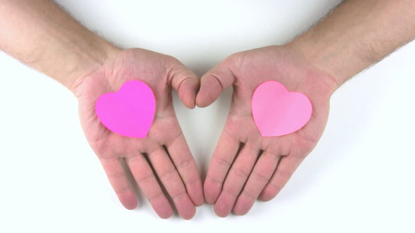 A person's palm with a pink heart-shaped stickers to reveal a white background