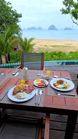 Savor a delicious breakfast spread featuring local flavors while overlooking the tranquil beach and breathtaking limestone formations in Krabi Thailand, setting a perfect start to the day.