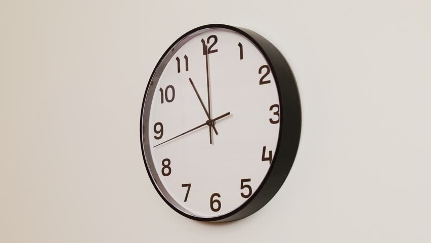 A close-up 4K shot of a classic black and white wall clock filling the frame, showing the time as 11:00 with the second hand at 9 rolling through the hour.