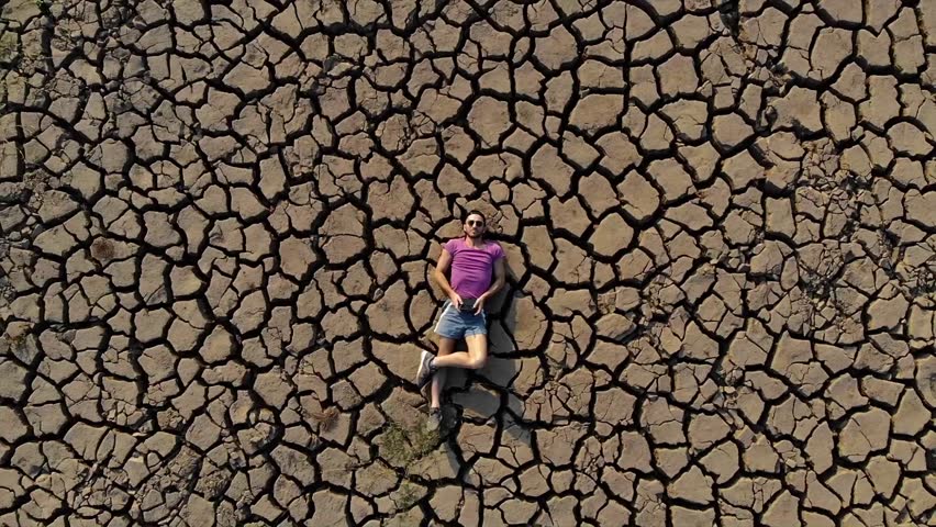 Drone Revealing a Person Lying on Cracked Dry Earth.