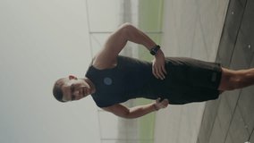 Focused young man in sports outfit pushes against a wall, showcasing determination and strength. A smartwatch is visible, highlighting a tech-savvy athlete. Vertical video. - Powered by Shutterstock - Get 15% off with code: PIKWIZARD15
