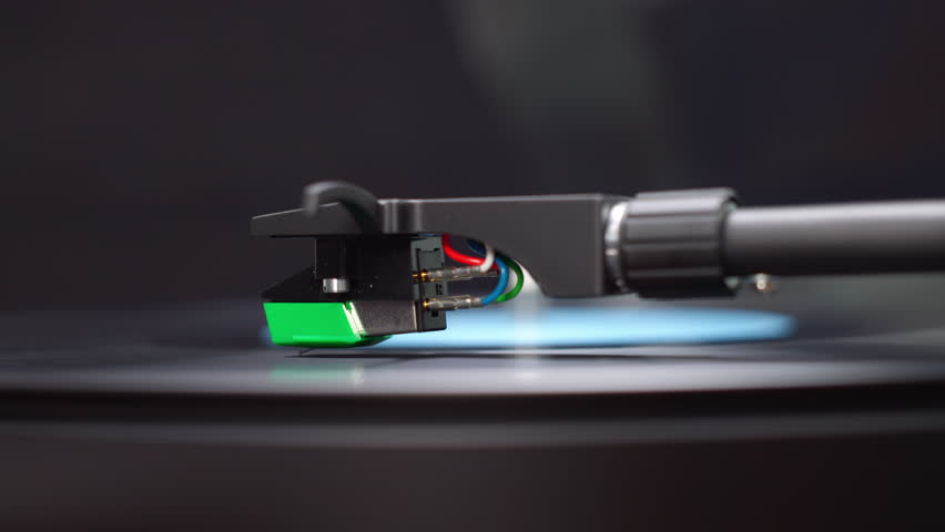 A macro shot of a record player stylus gently resting on the black vinyl's final grooves. The last song plays as the needle nears the record’s end.