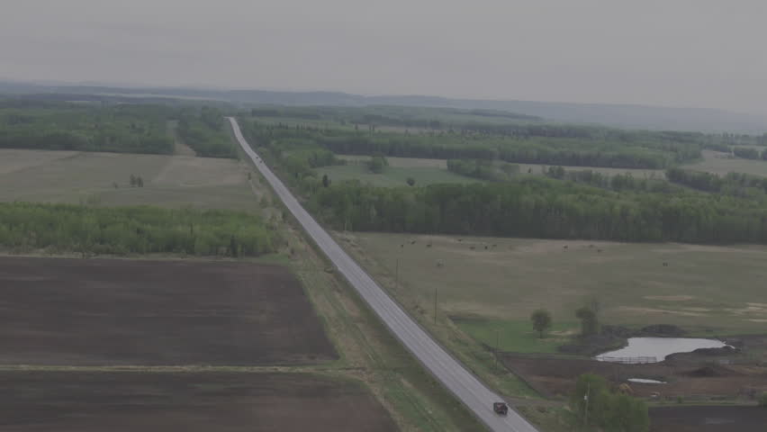Long stretch of road cutting through Northern Alberta farmlands