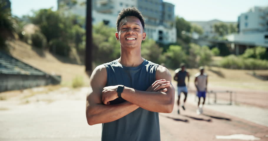 Face, man and confidence for fitness at stadium of hurdle sports, running exercise and track competition. Male person, arms crossed and pride for race practice, leadership and jump challenge on field
